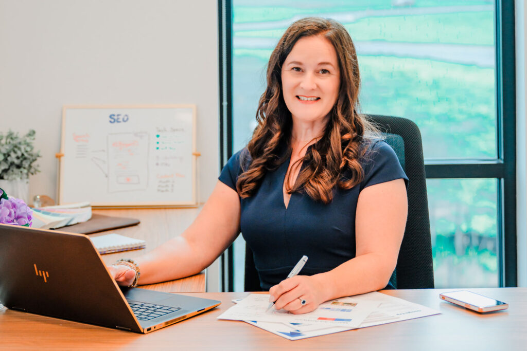 Digital marketing professional sitting at a desk with a laptop and SEO planning whiteboard, representing Inner Loop Media's native advertising services