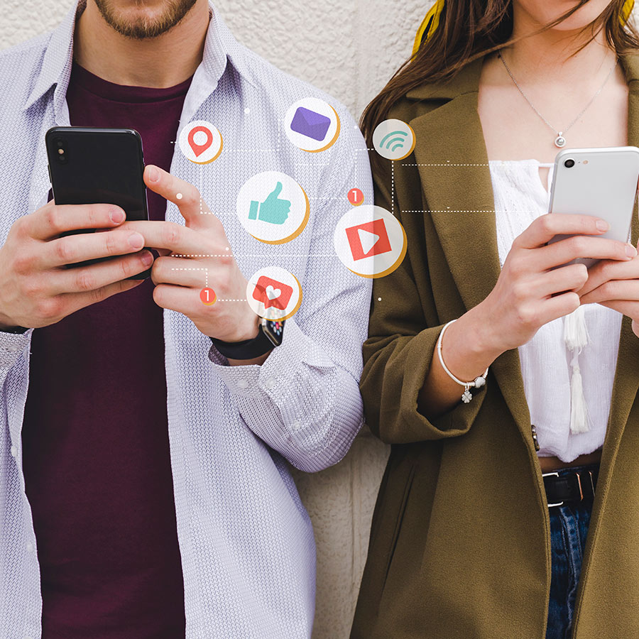 Two people using smartphones with floating social media icons like thumbs up, location pin, video play button, and heart notifications